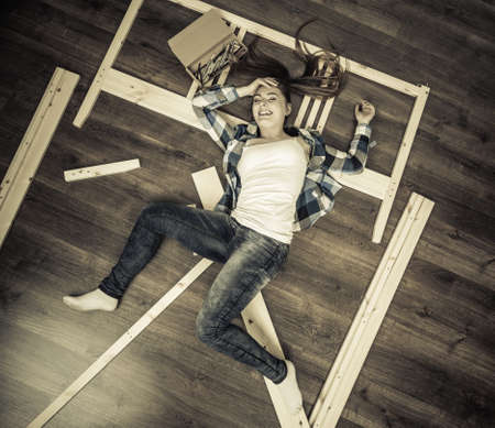 Happy woman having fun assembling furniture at home. Young girl laying on floor arranging apartment house interior. DIY. High angle view.の写真素材