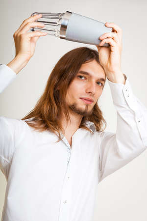 Alcohol liquor drinking party relax concept. Young bartender shaking glasses. Male barman holding glass and shaker preparing mixed beverage.の写真素材