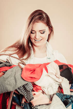 Daily routine in household laundry decide what to wear. Young excited woman hold pile of colorful clothes.の写真素材