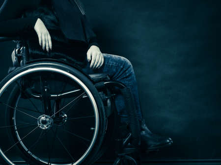 Real people, disability and handicap concept. Young woman invalid girl sitting on wheelchair part of body studio shot on blackの写真素材