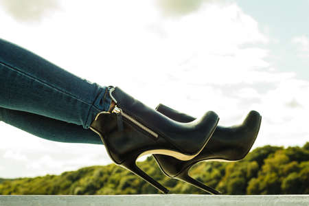 Autumn fashion outfit. Fashionable woman long legs in denim pants black stylish high heels shoes outdoor on city streetの写真素材