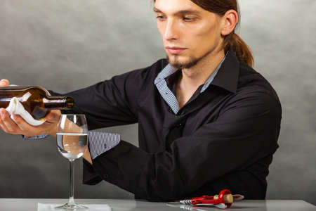 Alcohol liquor drinking tasting relax concept. Wine steward fills glass. Young male waiter pours drink into cup.の写真素材