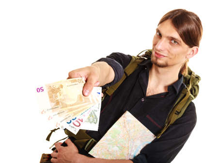 Man tourist backpacker paying with euro money holding map. Young guy hiker backpacking. Summer vacation travel. Isolated on white background.の写真素材
