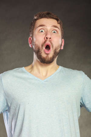 Portrait of shocked surprised amazed handsome man in shirt. Young guy posing in studio on black.の写真素材
