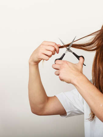Change of look.  Barber and hairdresser. Male hands with scissors trimmers cutting long brown hair.の写真素材
