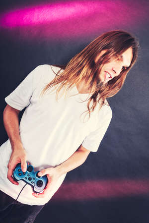 Addiction effects concept. Young unhappy depressed man with pad joystick playing games.の写真素材