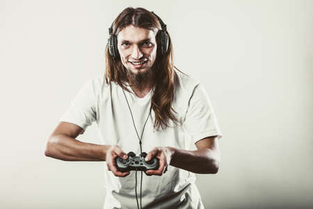 Playing games. Young smiling cheerful man play on console . Guy with pad joystick.の写真素材