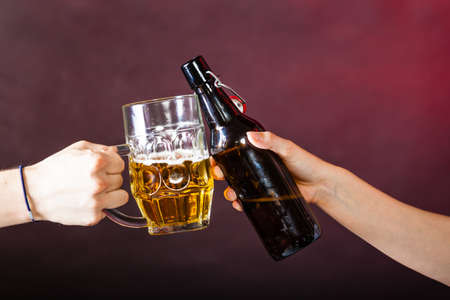 Drinking alcohol liquor party relax celebration concept. Closeup of beer toast. Two people colliding stein and ale bottle.の写真素材