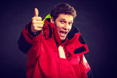 Cheerful man with weatherproof gear. Young male making thumbs up gesture. Adventure outdoors concept.の写真素材
