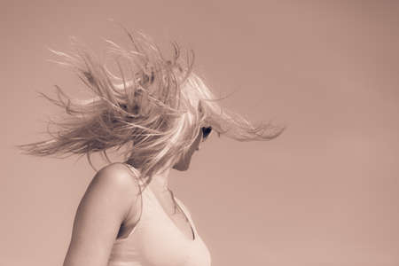Young blonde pretty girl on beach. Woman wearing sunglasses have active time in summer with crazy hair. Summertime concept copy space.の写真素材