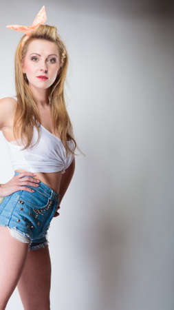pin up beautiful blonde fashion girl in hairband retro styling, studio shot gray backgroundの写真素材