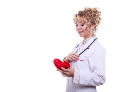 Periodic examinations. Cardiology concept. Female cardiologist holding red heart. Middle aged doctor with stethoscope and white medical apron uniform. Isolated on white.の写真素材