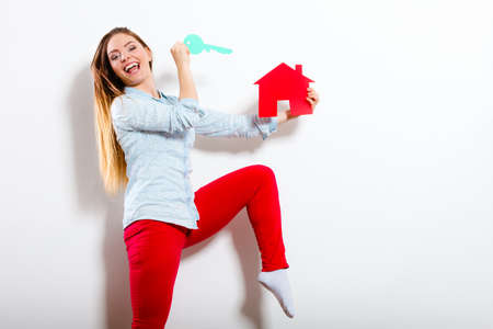 Happy young woman girl holding red paper house and key dreaming about new home house. Housing and real estate concept.の写真素材