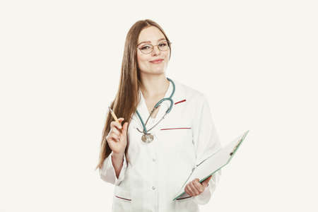 Woman medical doctor with stethoscope, clipboard and pen wearing white coat isolated. Professional health care.の写真素材