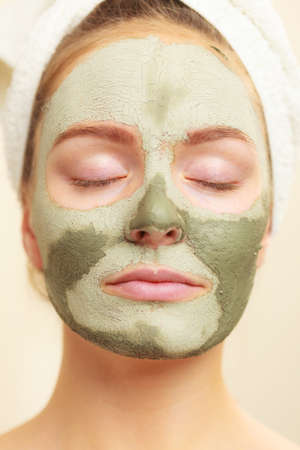 Skin care. Woman face with green clay mud mask close up. Girl taking care of oily complexion. Beauty...