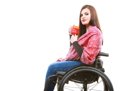 Real people, disability and handicap concept. Teen girl unrecognizable person sitting on wheelchair holding tea mug, studio shot on whiteの写真素材