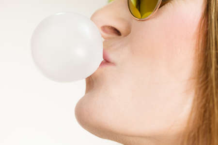 Fun leisure people concept. Funky girl blowing balloon. Chewing bubblegum. Young lady has beautiful sunglasses.の写真素材