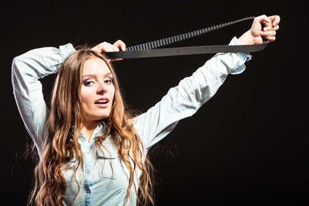 Sexy alluring woman holding fan belt. Strong girl feminist working in man profession. Gender social issue.の写真素材
