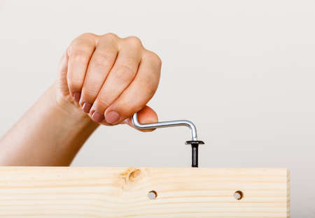 Human hand assembling wooden furniture using hex key. DIY enthusiast. Home improvement.の写真素材
