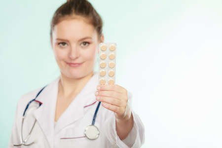 Ways of treatment. Pharmacist doctor in white medical unform apron showing pills. Woman specialist with stethoscope holding medication.の写真素材