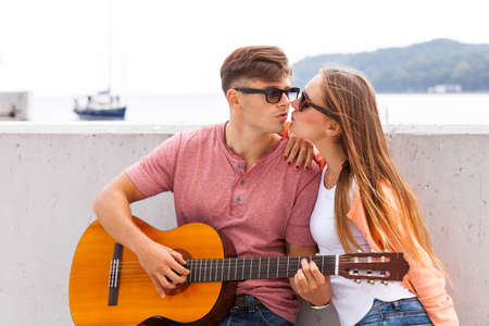 Love romance passion music dating concept. Girl kissing young guitarist. Teen lady showing her affection to male musican.の写真素材