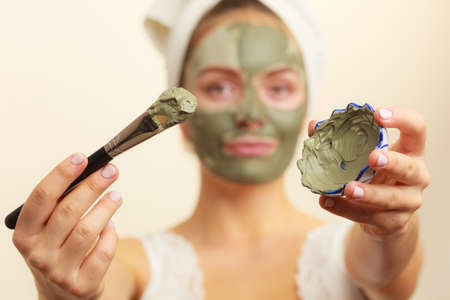 Skin care. Woman applying with brush clay mud mask to her face. Girl taking care of oily complexion. Beauty treatment.の写真素材