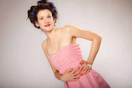 Teen girl preparing to party getting ready for going out. Young woman with hair curlers pin up makeup studio shot on gray. Hairstyleの写真素材