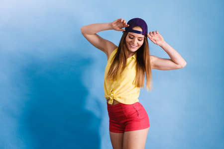 Woman casual style teen girl cap on head long hair posing on blue. Youth style. Fashion shot.の写真素材