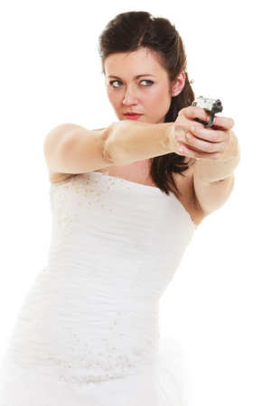 Wedding Day. Angry betrayed bride concept. Woman in white dress with gun isolated on white. Studio shot.の写真素材