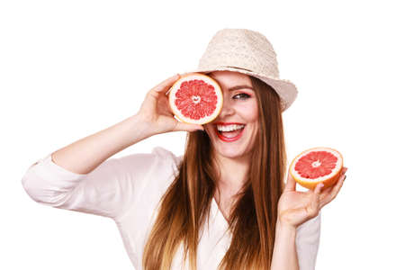 Woman attractive long hair girl holding grapefruit fruits slices for her eyes on white. Smiling female recommending healthy food. Summer holidays happiness conceptの写真素材
