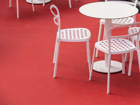 View on empty white table and chairs in outdoor restaurant.