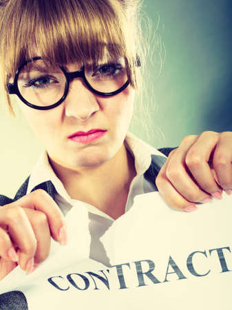 Business, documents and legal concept - serious unhappy businesswoman tearing crumpled contract
