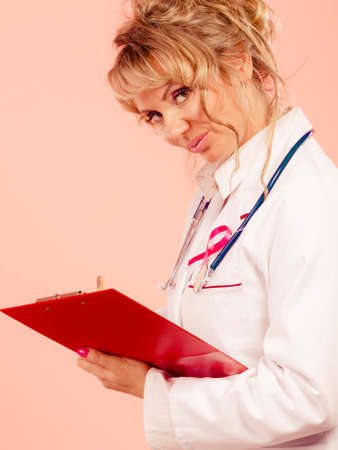 Diagnosis of breast cancer. Blonde middle aged female holding red folder with files of desease diagnose. Specialist inform patient about results.の写真素材