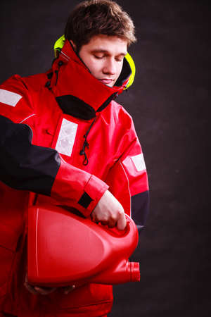 Man in oilskin with bottle fuel tank. Young male in waterproof jacket.の写真素材