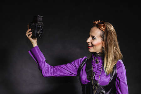 Photography and retro style. Young vintage attractive girl holds old aged camera. Steampunk photographer taking photo.の写真素材