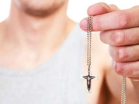 Man holding crucifix cross pendant necklace. Catholicism, christianity, religion symbol.