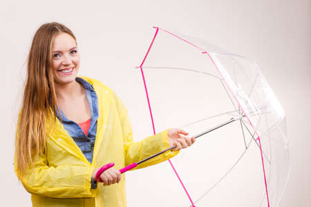 Woman rainy smiling girl wearing waterproof yellow coat standing under umbrella having fun....