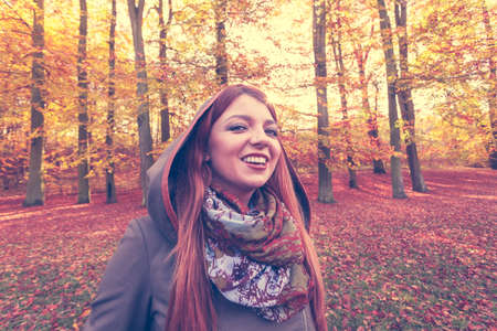 Nature, outdoors concept. Ginger hair girl in the forest. Young lady is enjoying good autumnal weahter.の写真素材