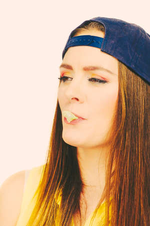 Woman casual style teen girl cap on head colorful makeup doing bubble with chewing gum closeup....