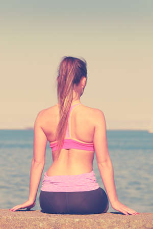 Woman resting relaxing after doing sports outdoors. Fitness girl female in sportswear on seaside takes breakの写真素材