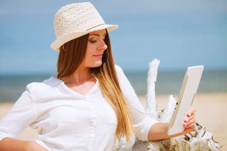 Young pretty woman with tablet pc computer on beach. Technological resting, summer, vacation.の写真素材
