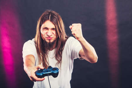 Addiction. Stressed depressed young man playing gaming on pad. Angry guy with controller pad play console. Face expression.の写真素材