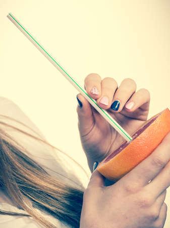 Woman holding grapefruit citrus sipping juice from fruit. Healthy diet food. Summer vacation holidays concept. Toned imageの写真素材