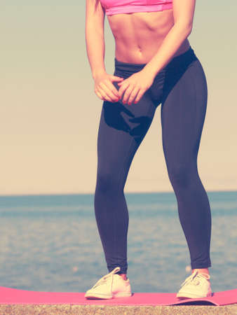Woman doing sports outdoors. Fitness girl in sportswear on seaside exercising keep her body muscles fitの写真素材
