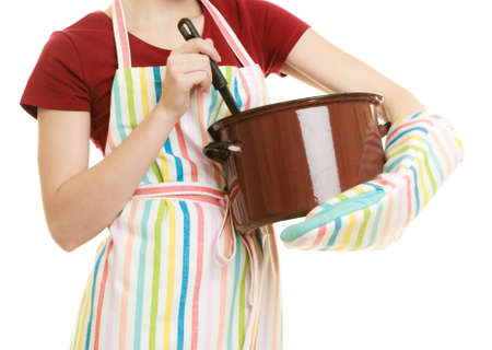Happy housewife or chef in colorful kitchen apron with pot of soup and ladle isolated studio shotの写真素材