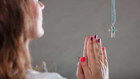 Woman praying to god jesus christ with cross necklace pendant. Strong christian religion faith. Christianity.の写真素材