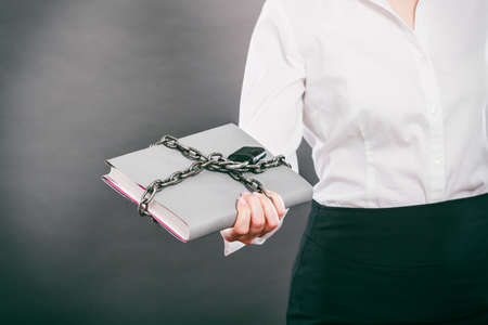 Human holding document file chained with padlock. Confidential secret data.