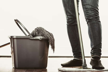 Closeup of human cleaning mopping floor. Person with mop and bucket at home. House cleanup.