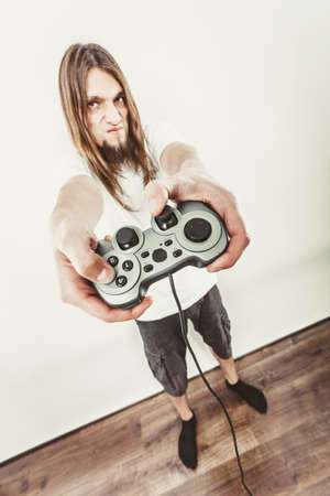 Addiction. Stressed depressed young man playing gaming on pad. Angry guy with controller pad play console. Face expression.の写真素材