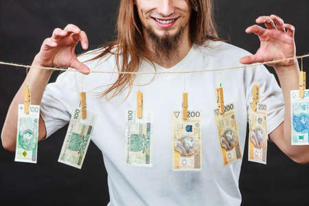 Riches and fortune. Young happy man with a lot of money on black background. Winning the lottery concept.の写真素材